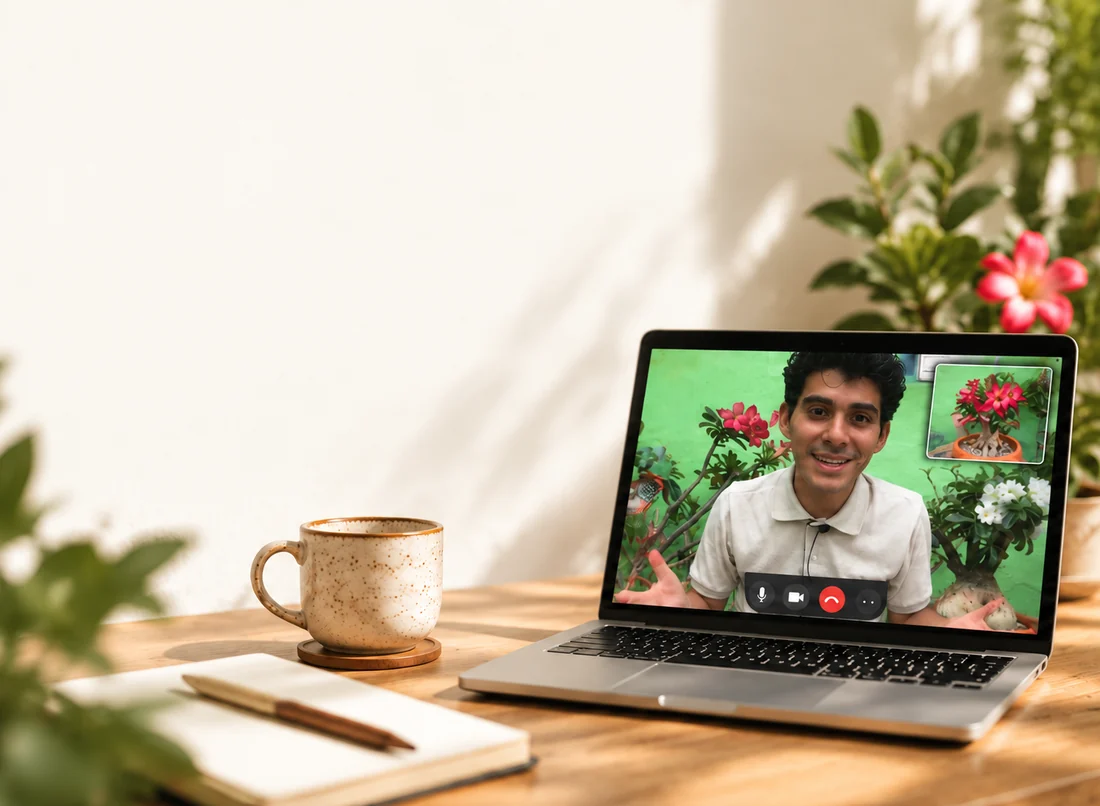 Computadora portátil con una videollamada sobre plantas, junto a una taza y un cuaderno